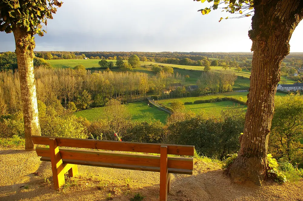 Prairies et haies du bocage des Coëvrons, vues depuis un banc à la lumière du soir